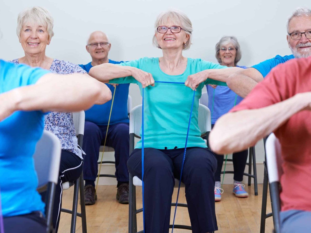 senior citizens participating in a low-impact chair aerobics class